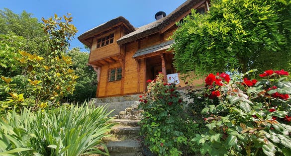 A wooden cabin surrounded by flowers and bushes in a botanical garden in Szeged, Hungary