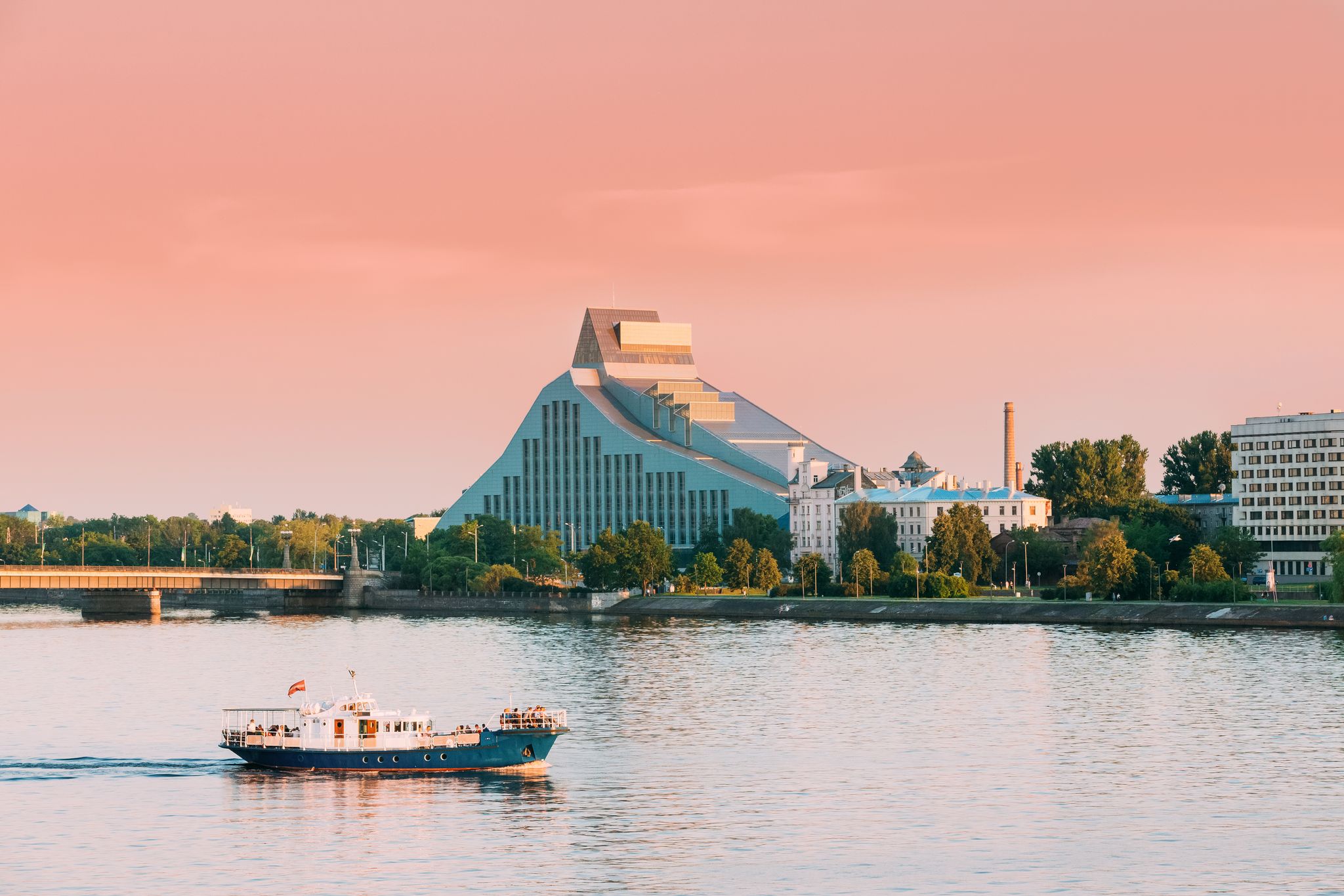 Riga, Latvia. Pleasure Boat Floating On Daugava River With View Of National Library On Background.