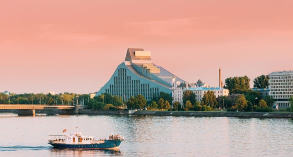 Riga, Latvia. Pleasure Boat Floating On Daugava River With View Of National Library On Background.