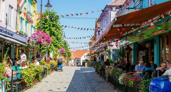 Photo of tourists on historical street in Stavanger old town with multicolor wooden houses.