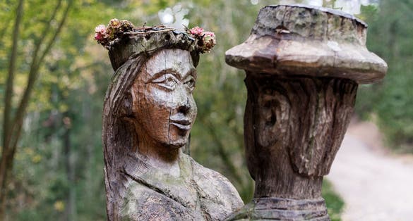 photo of old wooden sculpture in the forest, a man and a woman dancing .Witch hill park, Lithuania.