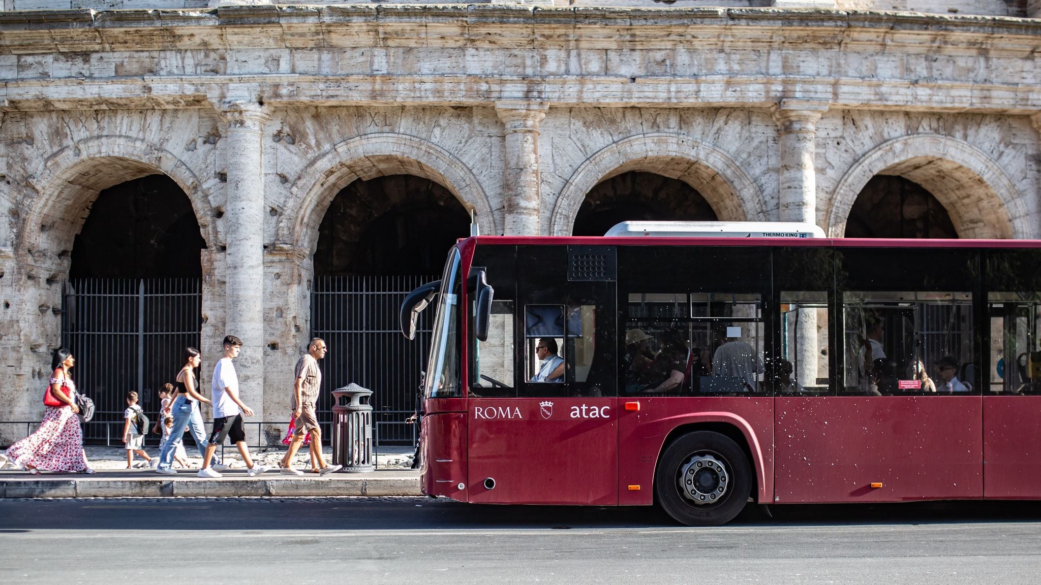 Tourists and public bus near the Colosseum on a sunny afternoon in Italy in June..jpg