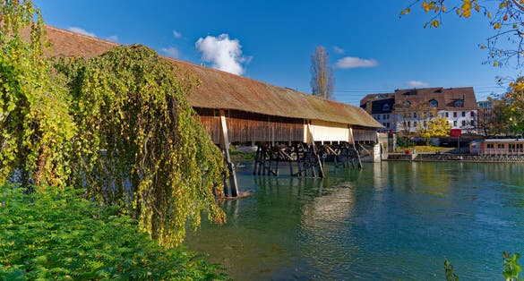 Photo of beautiful covered wooden bridge over Aare River at the old town of Swiss City of Olten on a sunny autumn day, Switzerland.