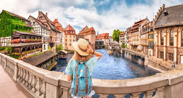 Photo of girl standing on a bridge over d Ill river in Strasbourg, France.
