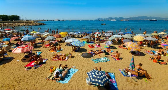 A crowd of vacationers enjoy the warm beaches of Cannes, France during the summer.