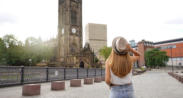 Photo of tourist girl walking in Manchester city on sunny day, England, United Kingdom.