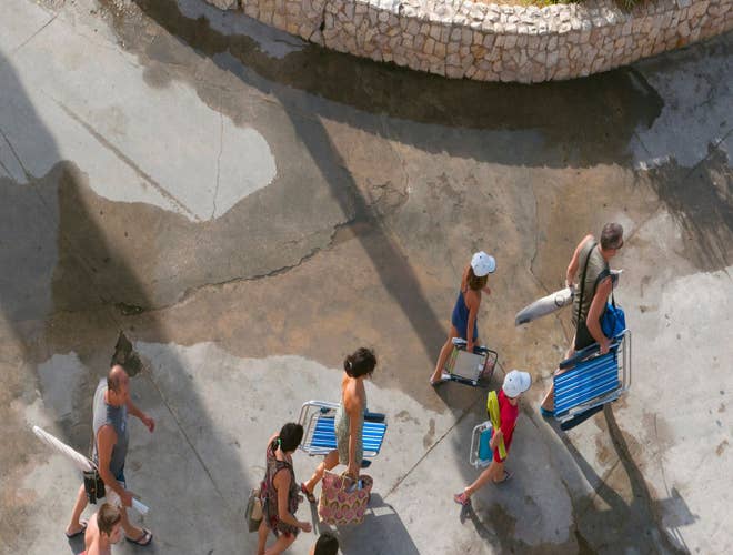 Families carrying beach gear on a sunny walk, heading for a seaside day in Portugal in August..jpg