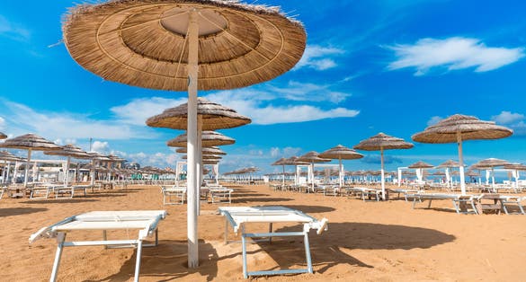 Photo of Umbrellas and chaise lounges on the beautiful beach of Rimini in Italy.