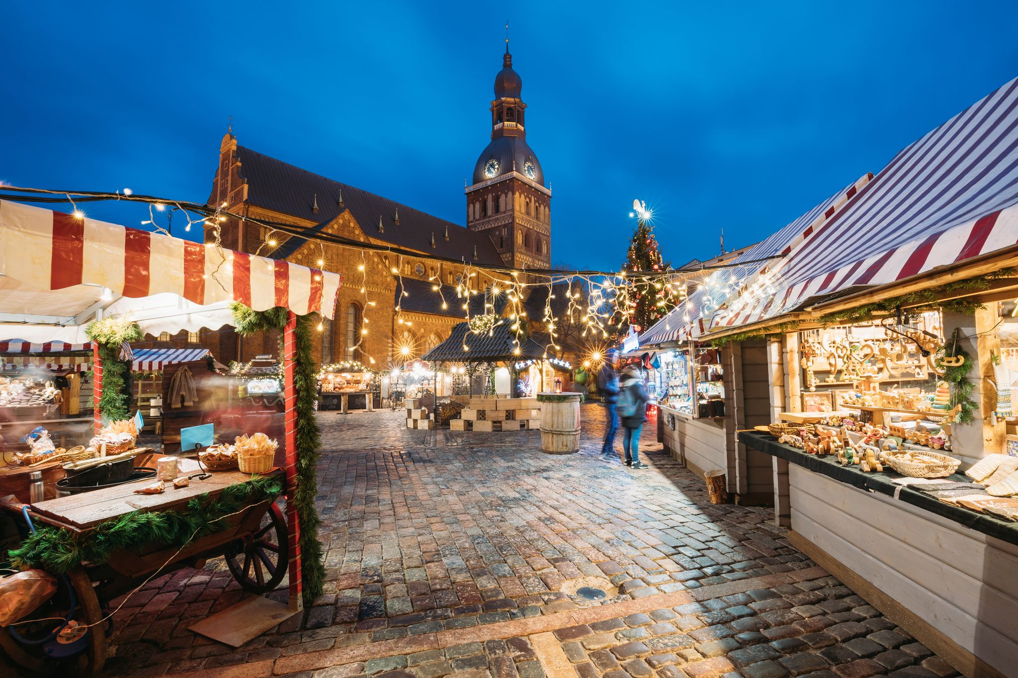 photo of Riga, Latvia. Christmas market on dome square with Riga dome cathedral. Christmas tree and trading houses. Famous landmark at winter xmas evening night In Illuminations Light.