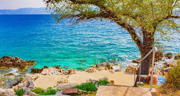 Beautiful Mediterranean landscape promenade in Novi Vinodolski Croatia behind a tree.