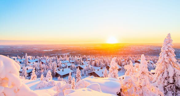 Photo of stunning sunset view over wooden huts and snow covered trees in Kuusamo ,Finland.
