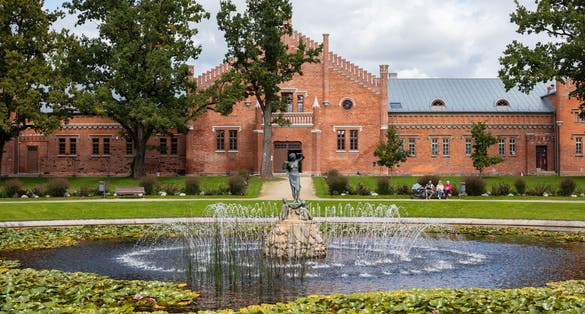 photo of Plunge, Lithuania - September 5, 2021: View to the fountain and mews of plunge manor or oginski residential manor (1879).
