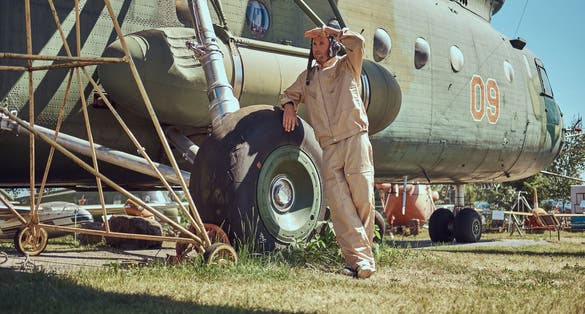 Photo of Mechanic in uniform and flying near the large military helicopter in Aviation Museum in Belarus.
