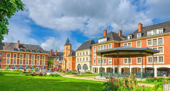 Bandstand band shell music pavilion stage in Square Jules Bocquet, lawn with green grass and flowers and Maison du Sagittaire Sagittarius house in Amiens city centre, Hauts-de-France Region, France