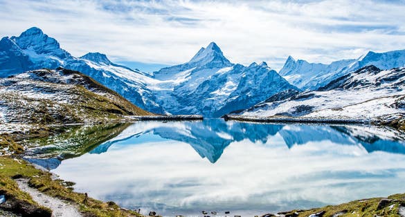 Photo of Swiss alps water reflection in Bachalpsee - mountain lake above Grindelwald, Switzerland.