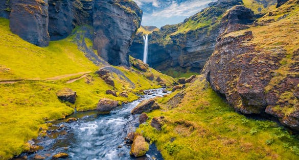 photo of View from flying drone. Yellow grass on the hills on Kvernufoss watterfall. Majestic summer view of pure water river in Iceland.