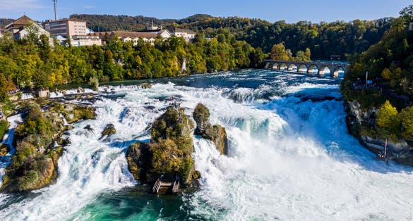 Rhine Falls, Rheinfall, Switzerland panoramic aerial view. Tourist boat in waterfall. Bridge and border between the cantons Schaffhausen and Zurich. Cliff-top Schloss Laufen castle, Laufen-Uhwiesen.