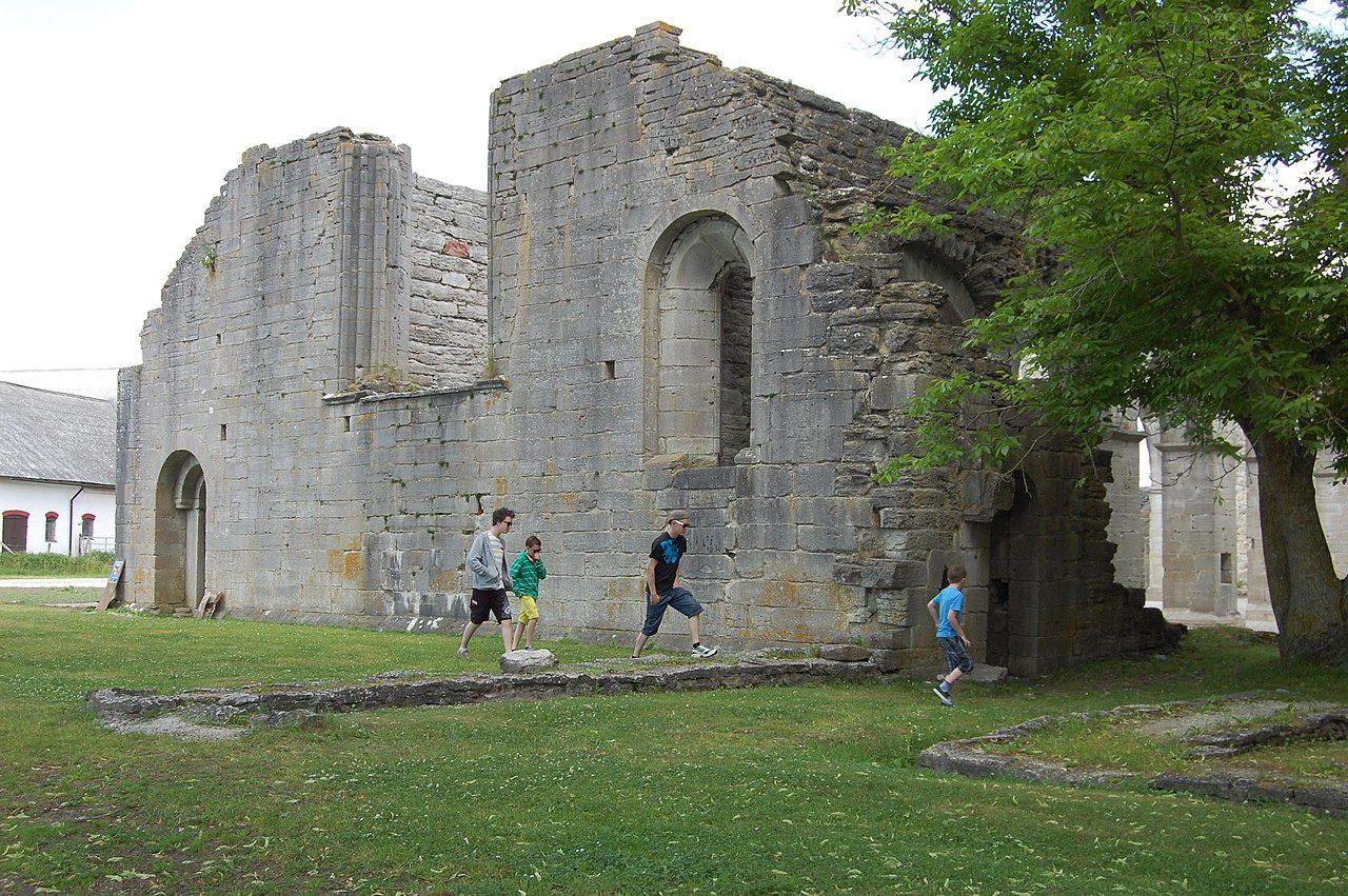 photo of the ruined abbey church, the west façade with children watching it in Gotland, Sweden.