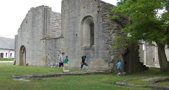 photo of the ruined abbey church, the west façade with children watching it in Gotland, Sweden.