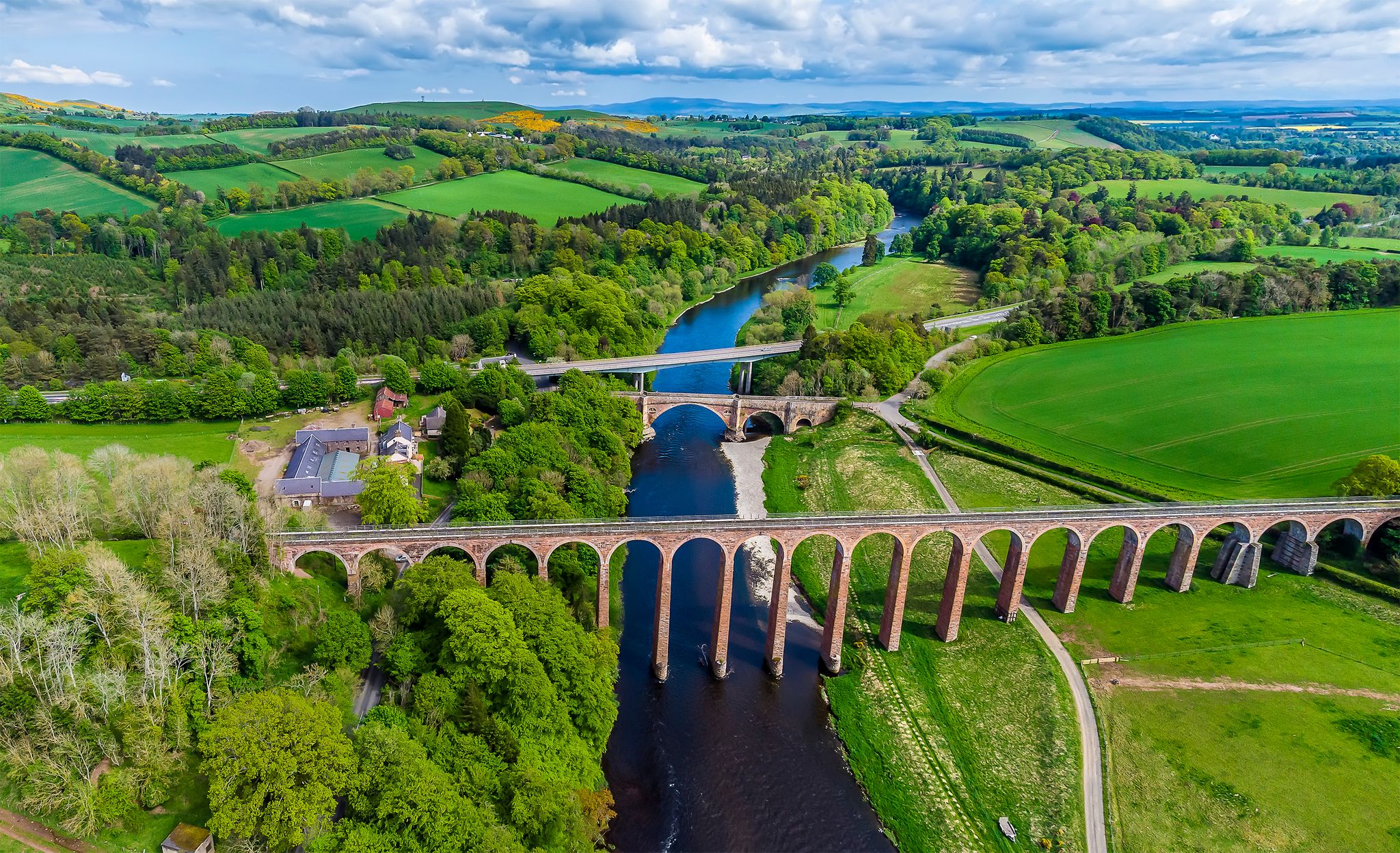 Photo of An aerial view of the Leaderfoot Viaduct, medieval bridge and modern road bridge in Scotland on a summers day .
