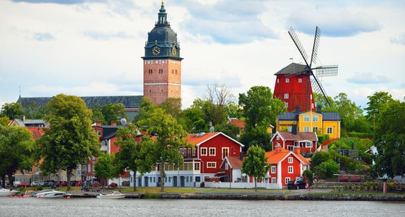 photo of panoramic cityscape from a sailing boat. Yacht marina, cathedral, traditional houses, windmill. Strängnäs, Mälaren lake, Sweden.
