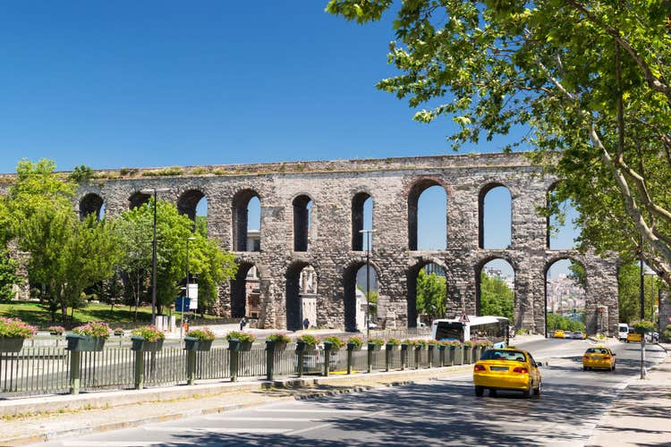 Aqueduct of Valens over city road, Istanbul, Turkey. It is old landmark of Istanbul. Cars drive on street in Fatih district in summer. Ancient Roman architecture, historic building in Istanbul town.