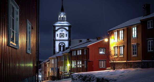 photo of view of The Roros Church stands amidst of traditional Scandinavian wooden homes, under a cloudy sky in this heritage-rich Nordic village