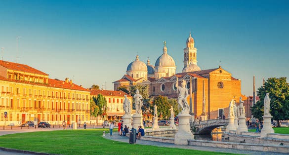 Prato della Valle square in historical city centre of Padua (Padova), elliptical square with green island at the center, small canal with statues, Abbey of Santa Giustina church, Veneto Region, Italy.
