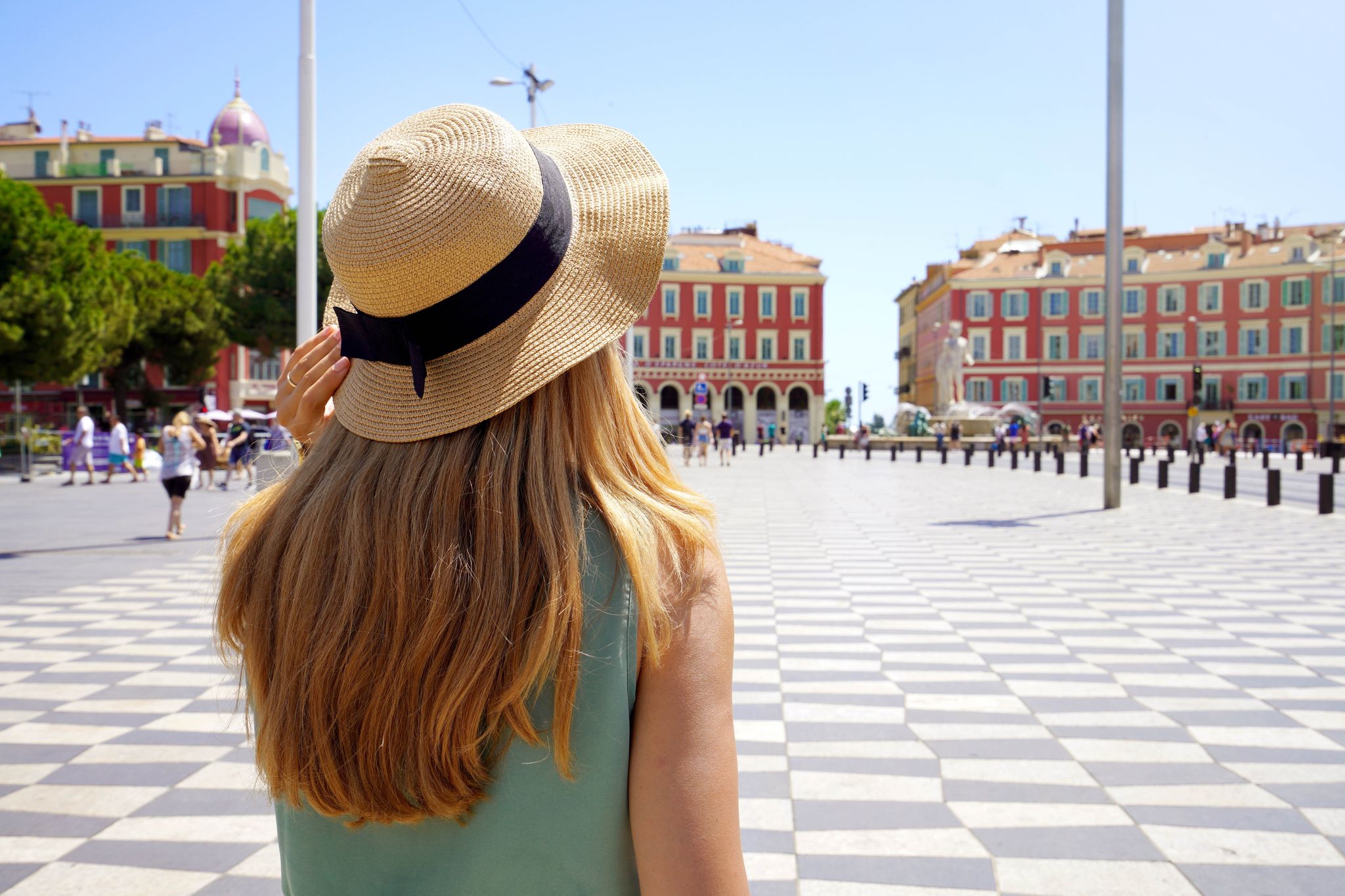photo of Tourism in France. Back view of young tourist woman walking in Massena square in Nice, France.