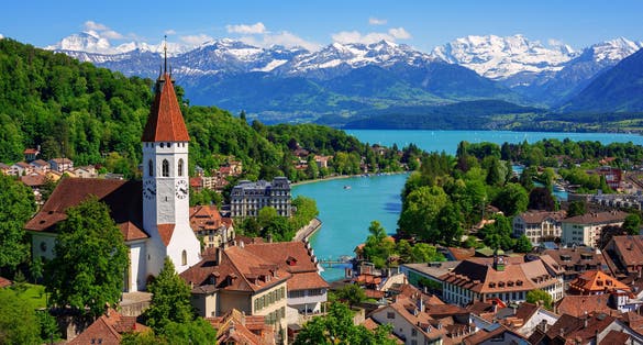 Photo of historical Thun city with snow covered Bernese Highlands swiss Alps mountains in background, Bern, Switzerland.