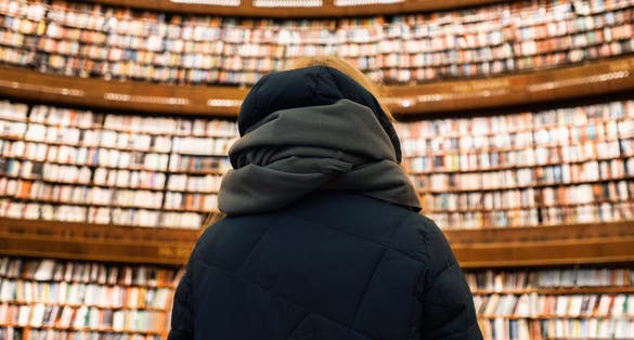 photo of a girl in a scarf in the Stockholm Public Library against the backdrop of several floors of books in Sweden.