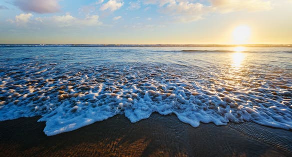Photo of Atlantic ocean sunset with surging waves at Fonte da Telha beach, Costa da Caparica, Portugal.