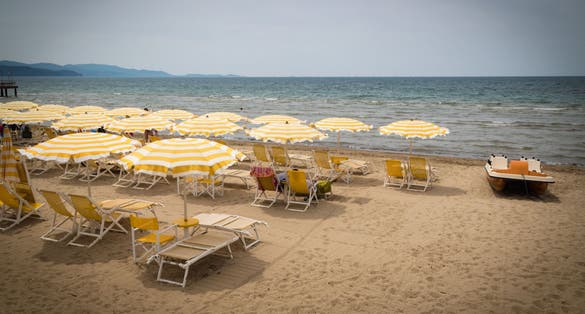 Golden beach with umbrellas and beach chair. Follonica, Grosseto, Italy