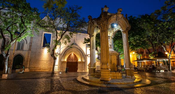 Photo of An evening view of the baroque fountain and exterior of Carmo Convent in Largo do Como in the beautiful city of Lisbon, Portugal.