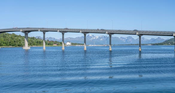 photo of view of concrete bridge with harbor in background, shot under bright summer light at Stokmarknes, Hadseloya, Vesteralen, Norway
