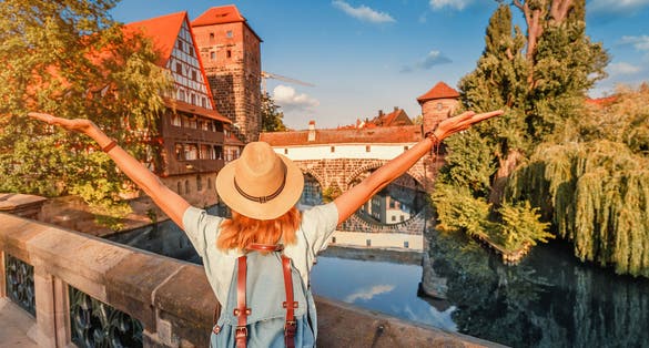Photo of woman tourist enjoying sunset view of the old town of Nurnberg city and Pegnitz river.