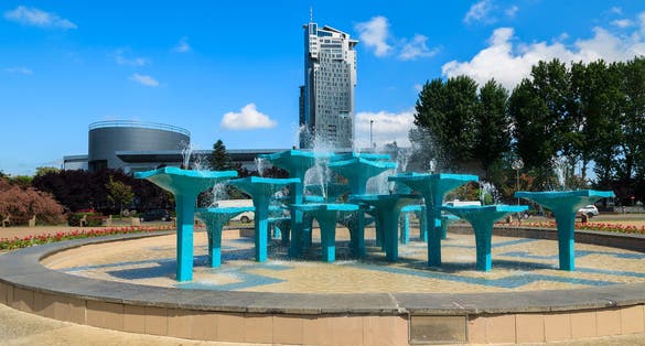 Photo of Water fountain in public park with view of tall tower building, Gdynia city waterfront, Poland