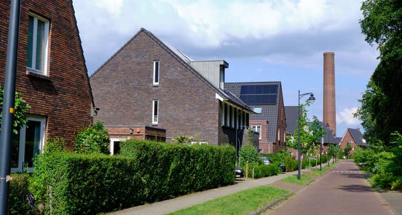 photo of street , new houses, old Enka factory site old chimney. New residential area after soil remediation in Ede, the Netherlands.