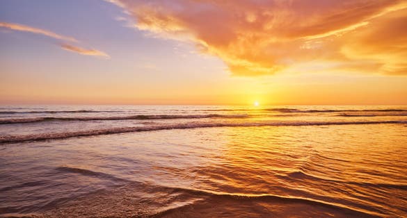 Photo of Atlantic ocean sunset with surging waves at Fonte da Telha beach, Costa da Caparica, Portugal.