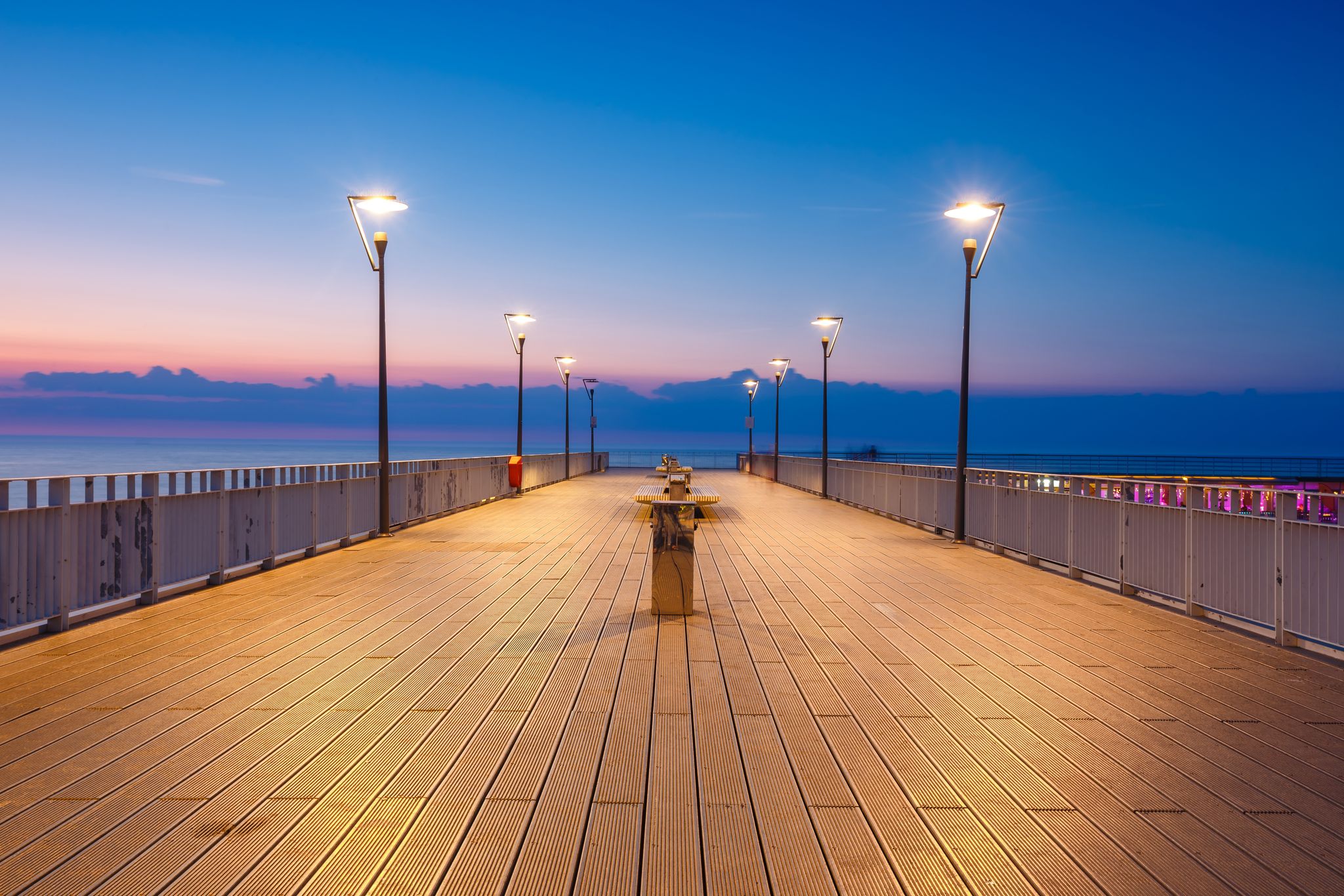 Photo of purple blue lights on the concrete pier on the Baltic Sea In the evening in Miedzyzdroje, Poland.