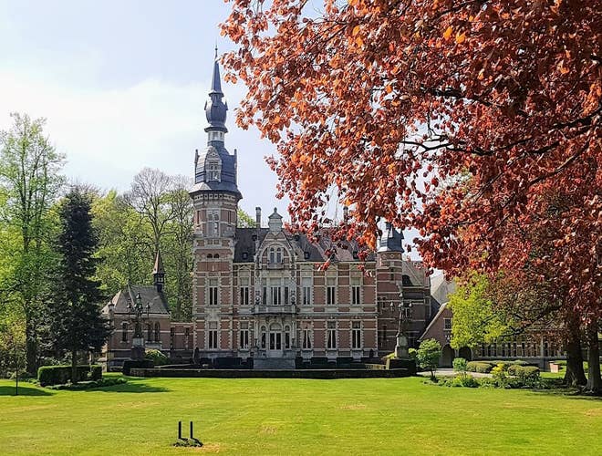 Majestic castle in Antwerp, framed by lush gardens and vibrant red autumn foliage..jpg