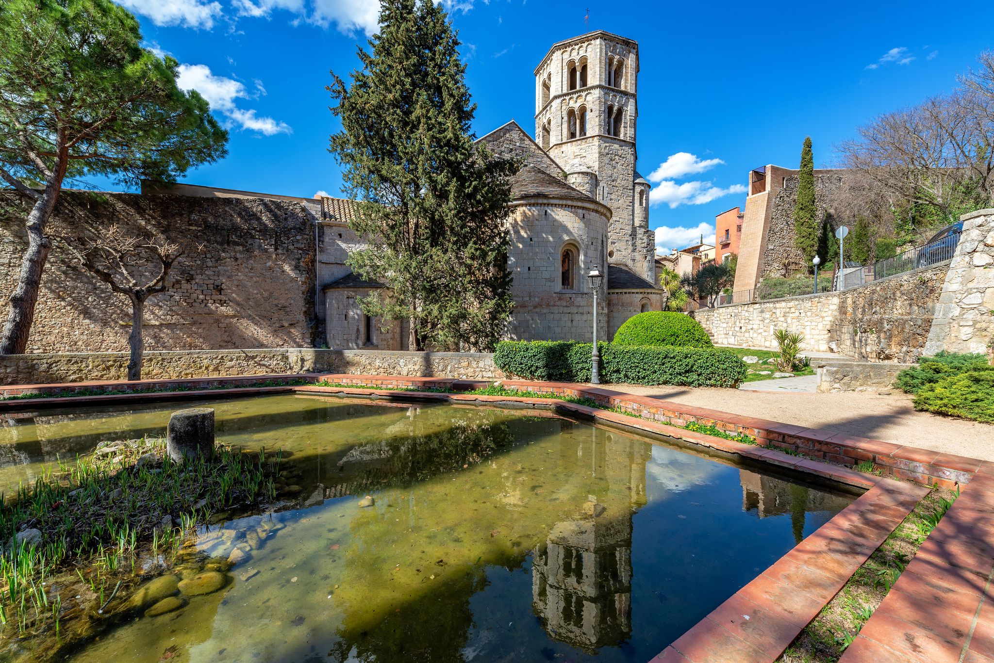 Photo of View of Sant Pere de Galligants Benedictine Abbey reflected in a pool of water in Girona, Spain.