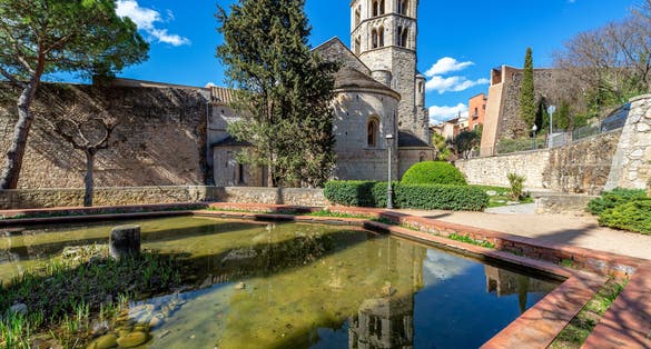 Photo of View of Sant Pere de Galligants Benedictine Abbey reflected in a pool of water in Girona, Spain.
