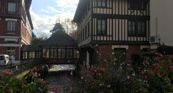 Photo of Flowers, river and normandy house, Lisieux, France.