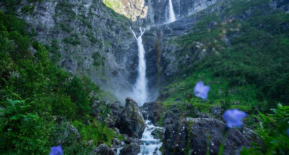 One of the highest waterfalls in Norway, Mardalsfossen, a summer landscape with a large waterfall with dense green vegetation and mountainous terrain.