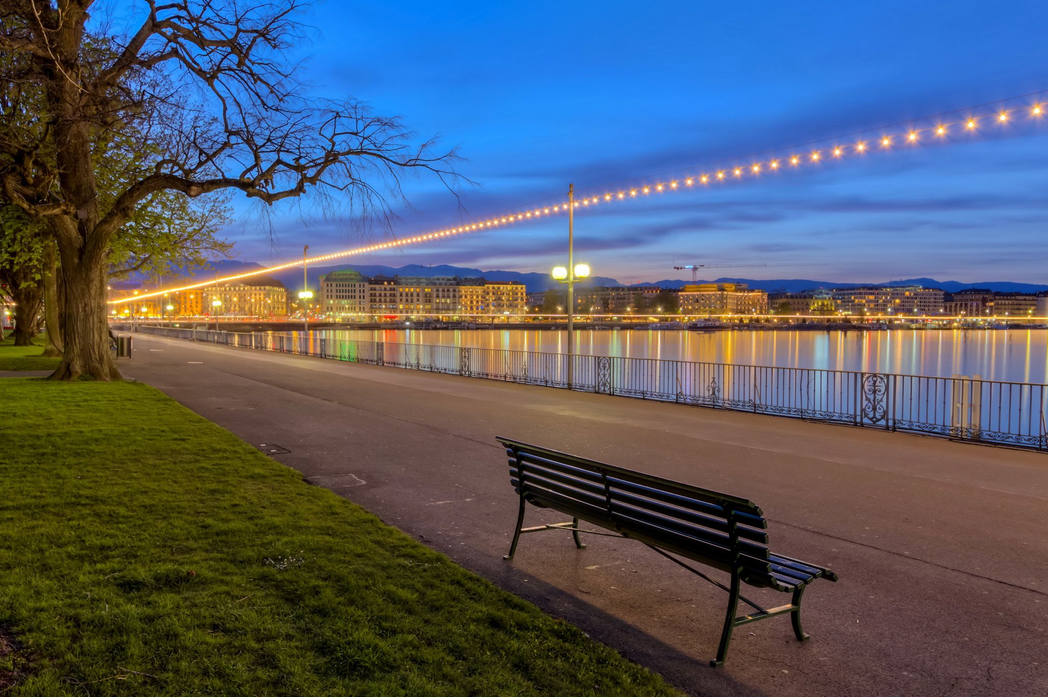 Photo of bench at the English garden promenade near the lake by night, Geneva, Switzerland.