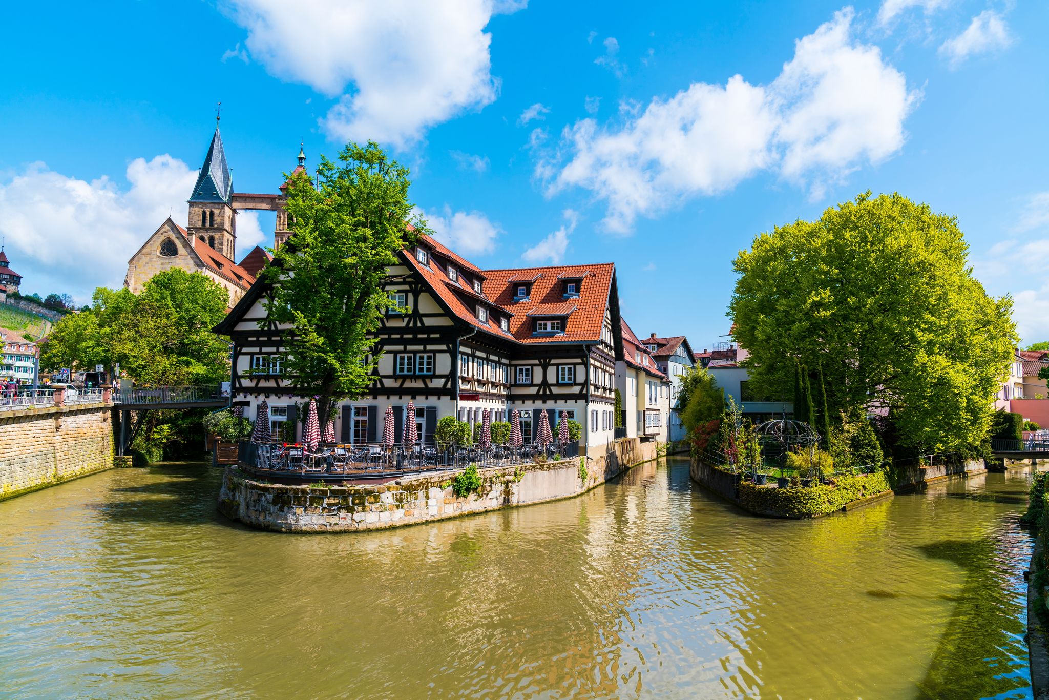 Photo of old town houses of Esslingen am Neckar city in summer with blue sky and sun next to Neckar river water, Germany.