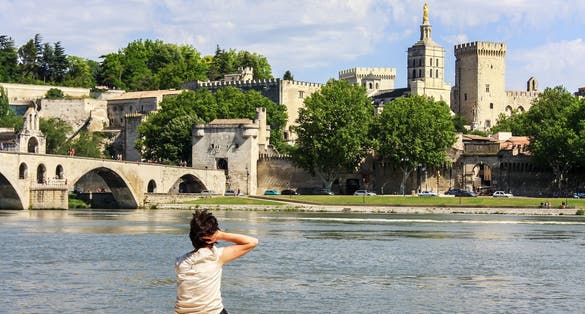 photo of a girl back view with Avignon cityscape with river Rhone and Palais des Papes in France.