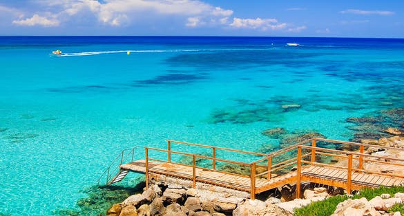 Photo of wooden platform with steps to azure sea water near Protaras, Cyprus island.