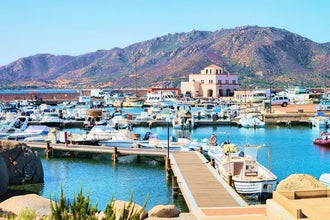 Colorful boats docked in Santa Teresa Gallura marina, with rugged Sardinian mountains rising in the background..jpg